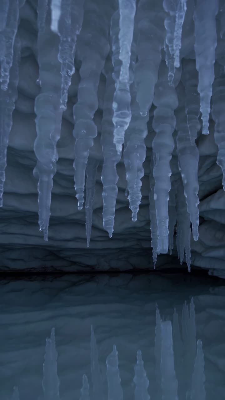 A mesmerizing video still of icicles hanging from a cave ceiling, captured from a low angle