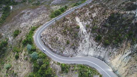 Toma-Aérea-De-Un-Coche-Conduciendo-Por-Una-Carretera-Ventosa-En-Tasmania,-Australia