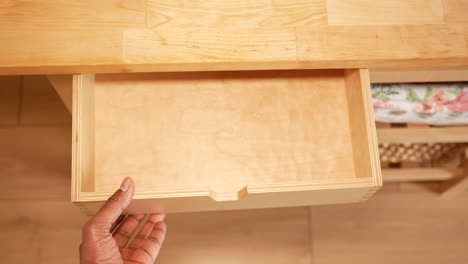 a person's hand opening an empty wooden drawer