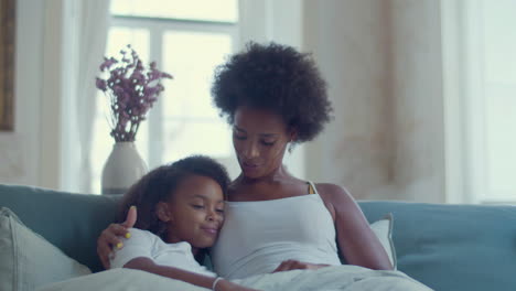 african american mother and daughter lying in bed and relaxing at home