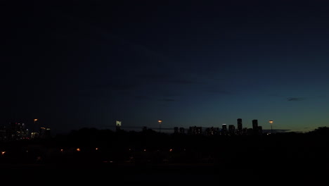 wide time-lapse shot of rapid city skyline sunset with fast moving vehicles and objects