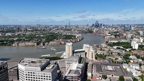 drone flight over the isle of dogs revealing sweeping views of the city of london skyline and the river thames capturing urban contrast and waterfront beauty from above.