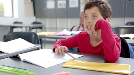 child in red shirt at desk with colorful school supplies, copy space