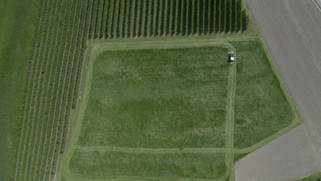 Tractor-Con-Cortacésped-Trabajando-En-Un-Gran-Campo-De-Hierba,-Vista-Aérea-De-Tierras-De-Cultivo