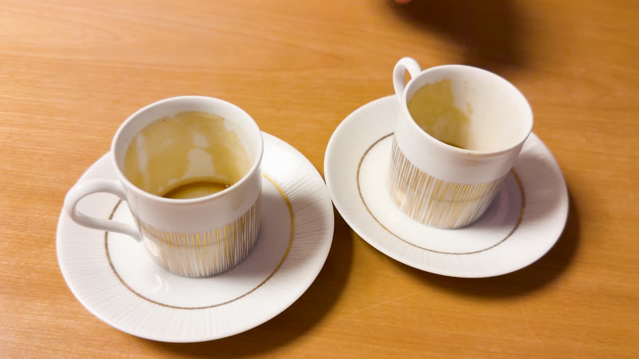 空のエスプレッソカップを、飲み終えた別のコーヒーカップの横のソーサーに置く手