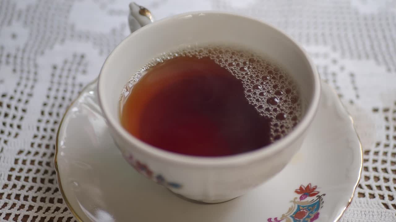 A cup of tea on a floral tablecloth