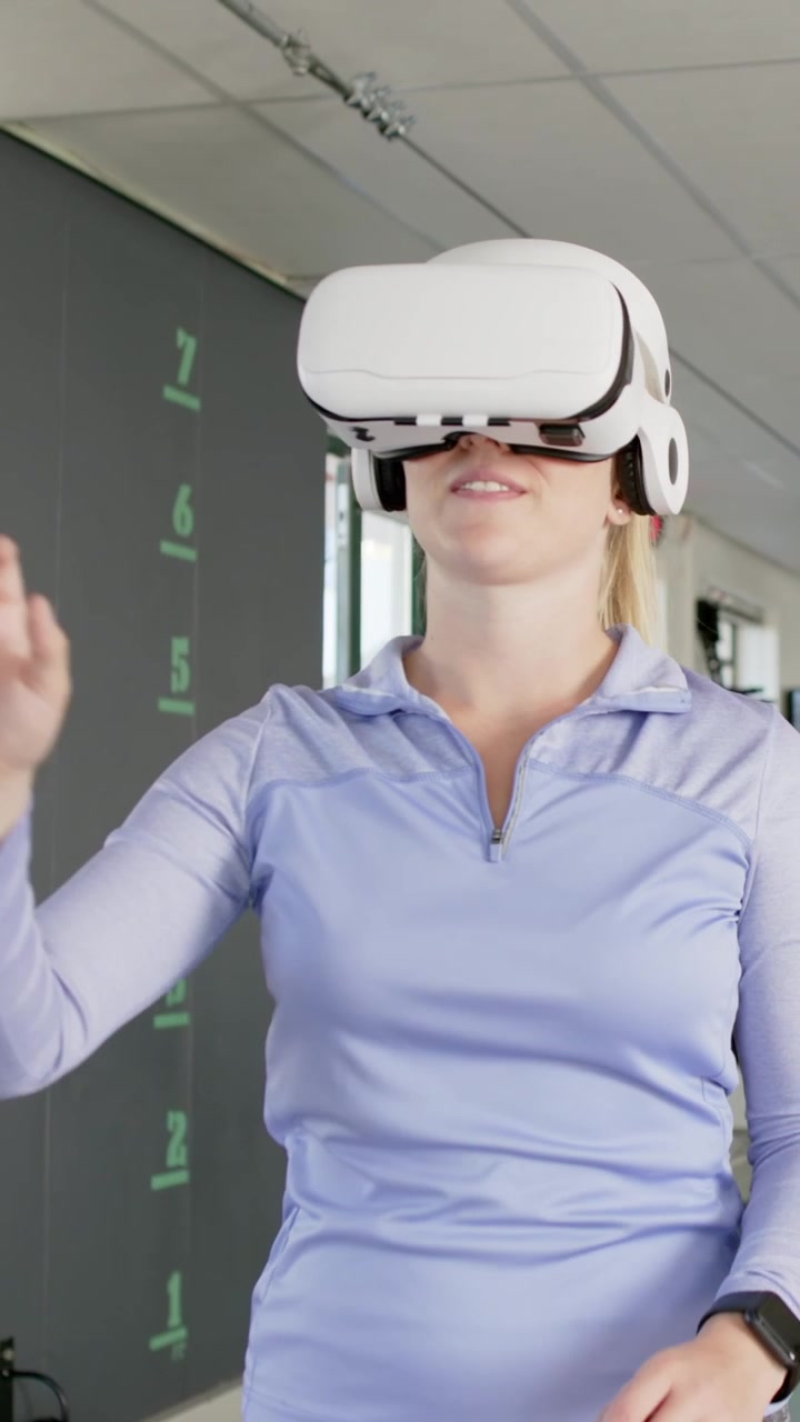 Video verticale: Donna adulta che indossa un visore VR e un top sportivo, testa l'interfaccia utente (UI) in scala in laboratorio.