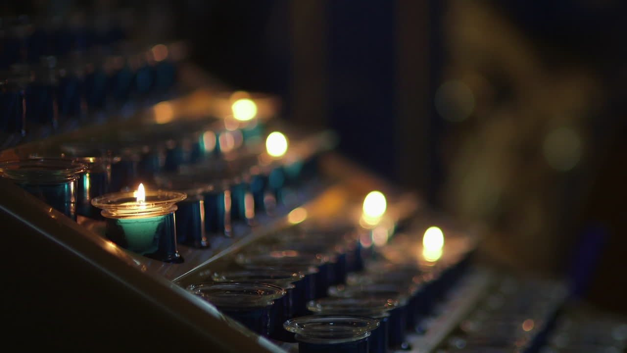 Primo piano di candele votive accese in un ambiente di chiesa buio
