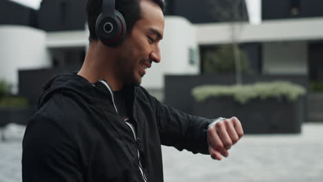 a man wearing headphones listens to music while looking at his phone on the street
