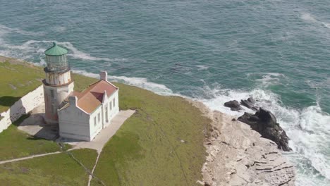 historic lighthouse on coastal cliffs, push in drone shot with tilt