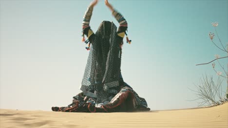 gypsy woman smiling and waving her hands on a desert sand dune