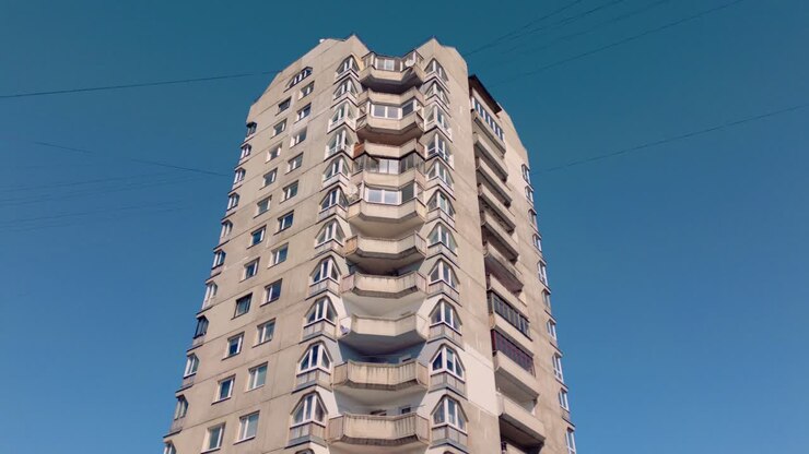 A filmagem mostra uma torre de apartamentos de concreto alta da década de 1950 no estilo arquitetônico brutalista e comunista, enfatizando seu design austero e funcional