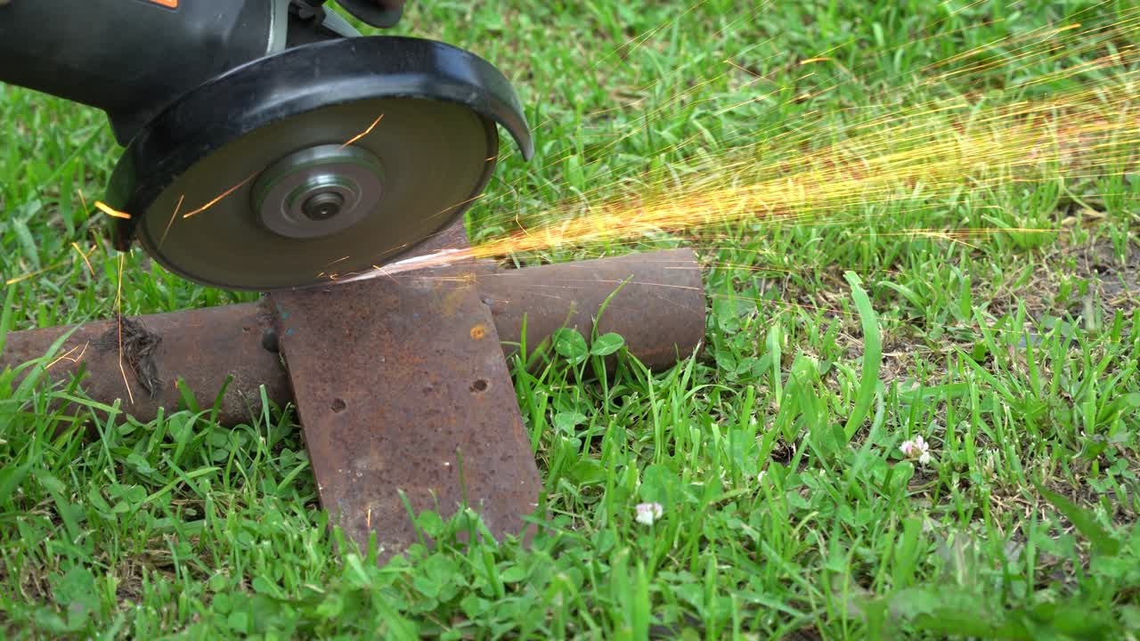 cortar metal en el césped con una herramienta de mano. chispas volando de hierro.