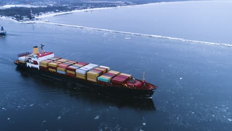 aerial shot of the cargo ship moving through the sea. in the background winter landscape.