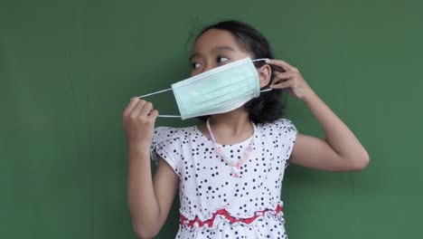 niña con máscara médica en pantalla verde, demuestra cómo usar máscara facial, máscara de procedimiento o máscara quirúrgica, contra bacterias y virus protección contra la pandemia epidémica
