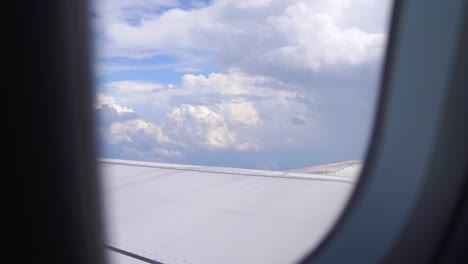 Vista-En-Cámara-Lenta-Fuera-De-La-Ventana-Del-Avión-Con-Cielo-Azul-Nublado