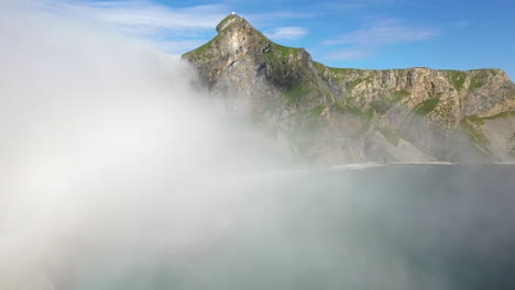 Wide-revealing-aerial-footage-of-a-rocky-coastline-and-beach-in-Vaeroy,-Lofoten-Islands-in-Norway