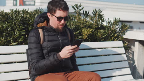 man using smartphone on a bench outdoors