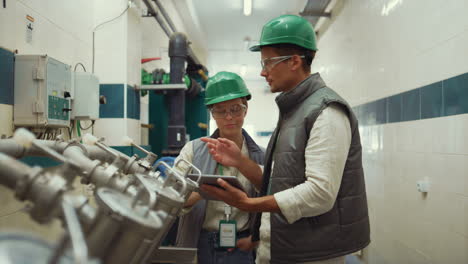 factory engineers check equipment in compartment. supervisors talk at machinery