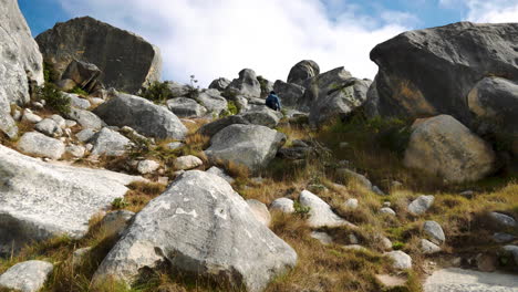 close up shot of tourist walking uphill between famous boulders on castle hill in new zealand