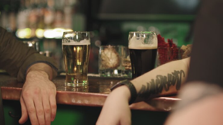 Uomini irriconoscibili con birra al bar.