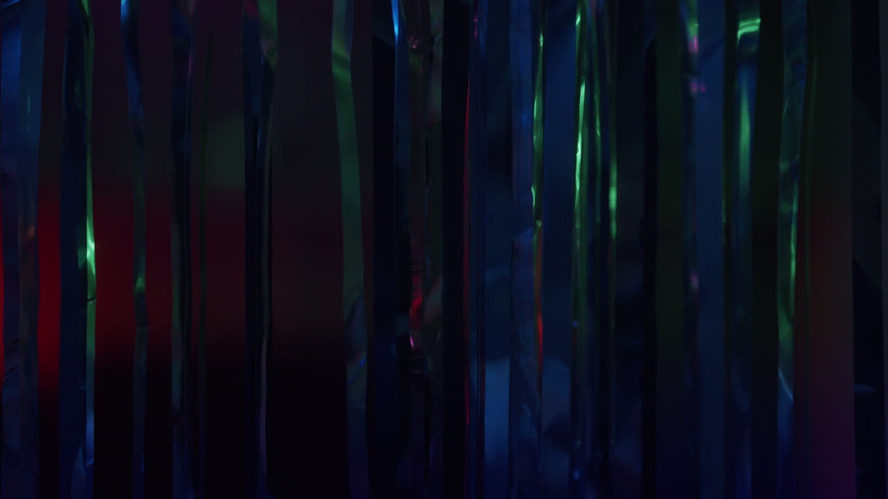 La mano di una giovane donna tocca una tenda sotto le luci al neon.
