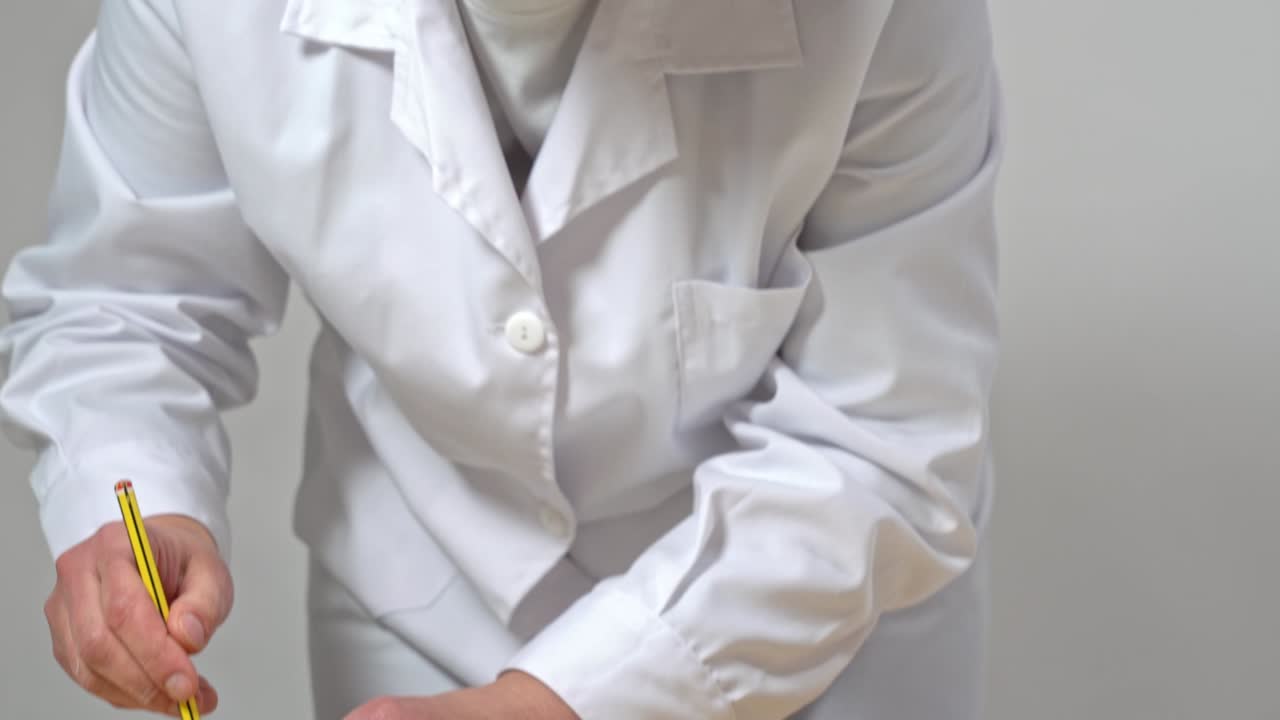 Baker using a pencil and a small metal cylinder to make circular shapes on parchment paper, to aid in making of macarons.