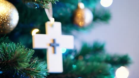 close-up of a white cross ornament hanging on a christmas tree