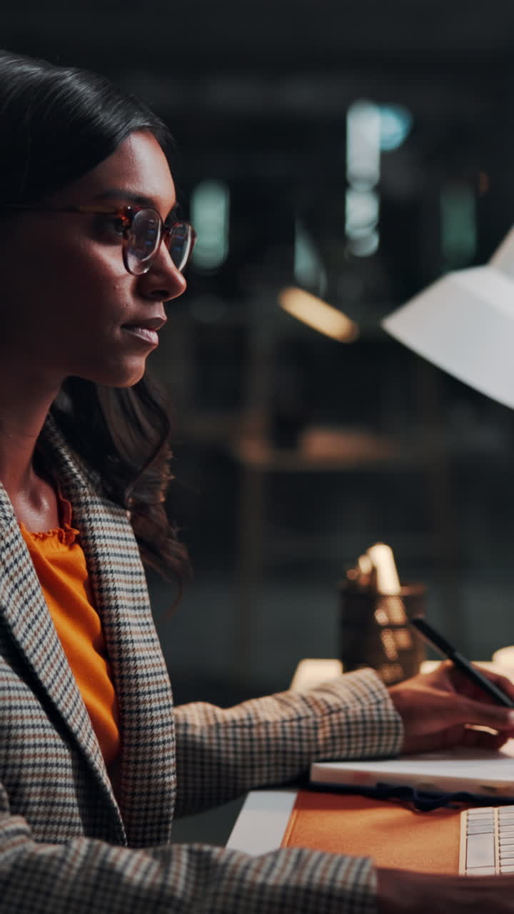 Young Woman Writing in Notebook at Desk in Office