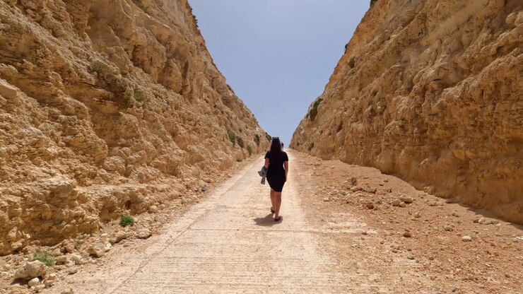 Giovane donna che cammina lungo un sentiero in un canyon ripido tra le scogliere