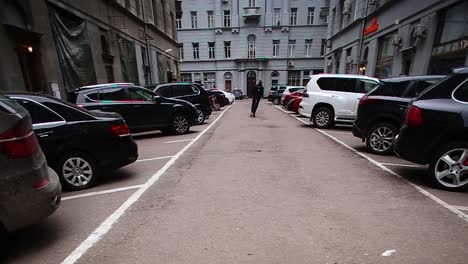 callejón de la ciudad con estacionamiento y persona en scooter