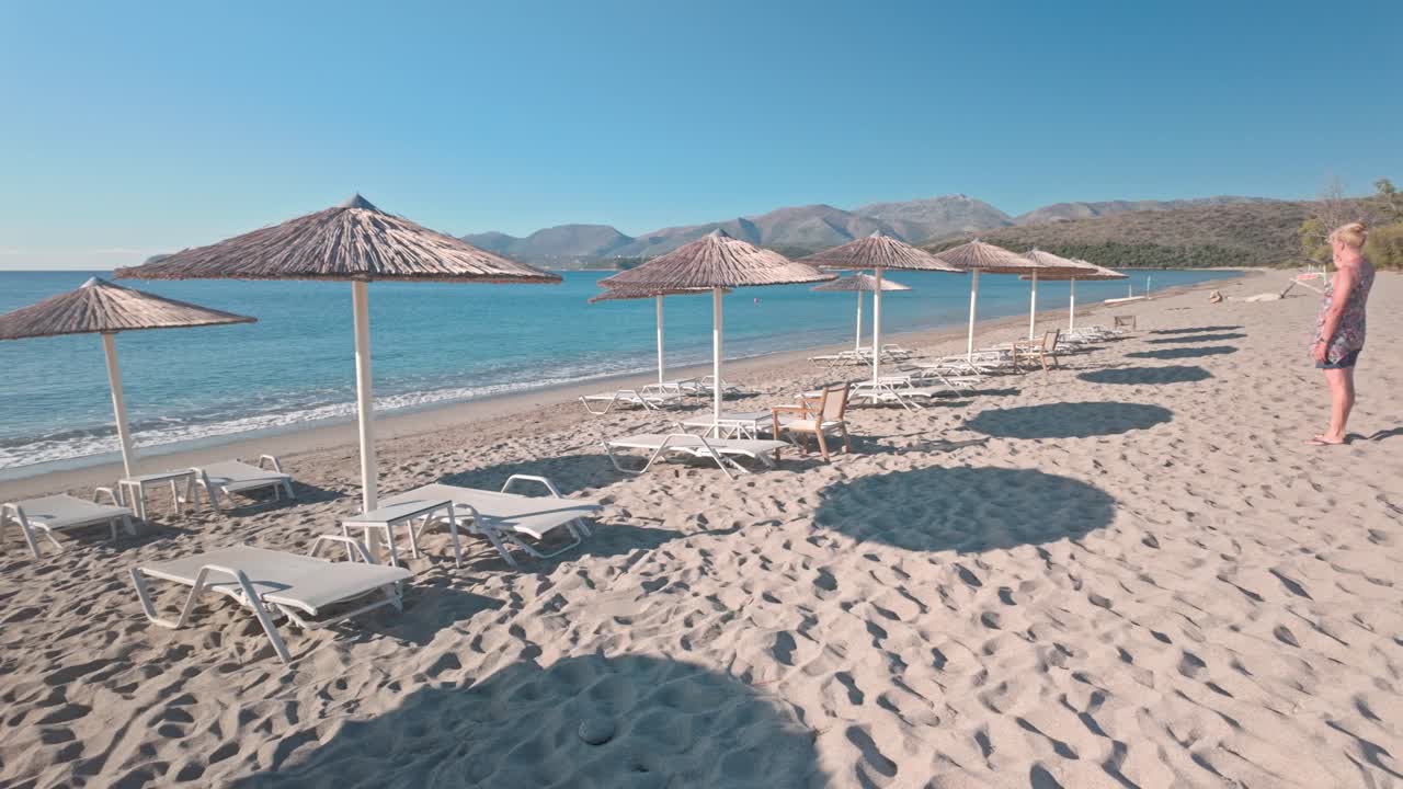 Woman relaxing on a beautiful beach with sunbeds and umbrellas