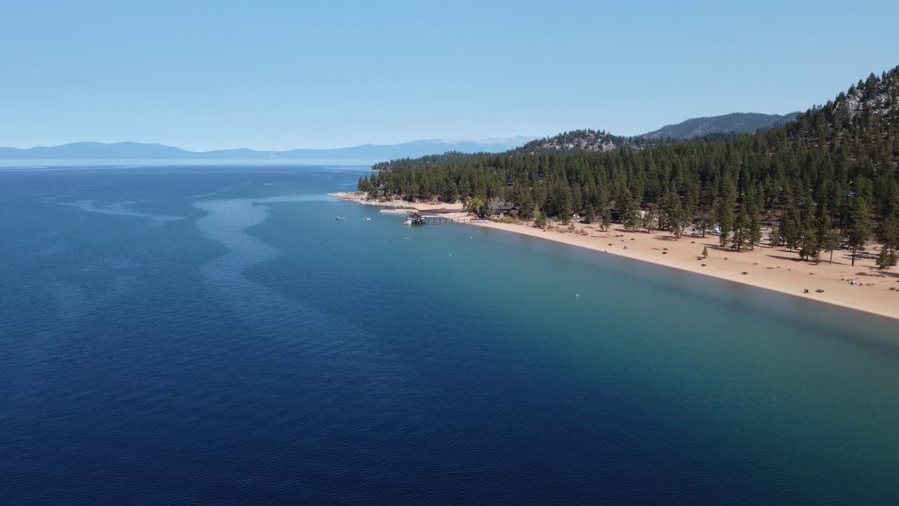 Ripresa con drone in senso orario di Nevada Beach, della foresta e dell'acqua cristallina del Lago Tahoe in una giornata limpida