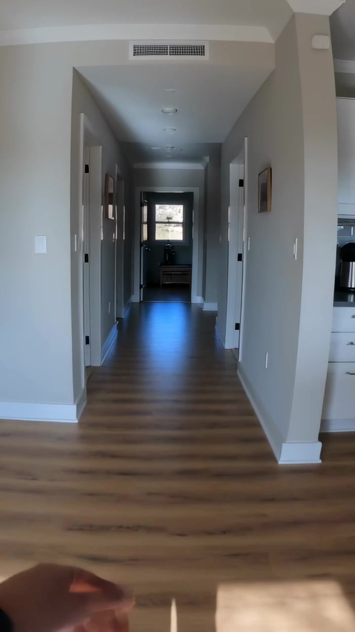 Video verticale: Riprese di un uomo che cammina lungo un corridoio di casa verso una finestra, tenendo il telefono guidato dal sole