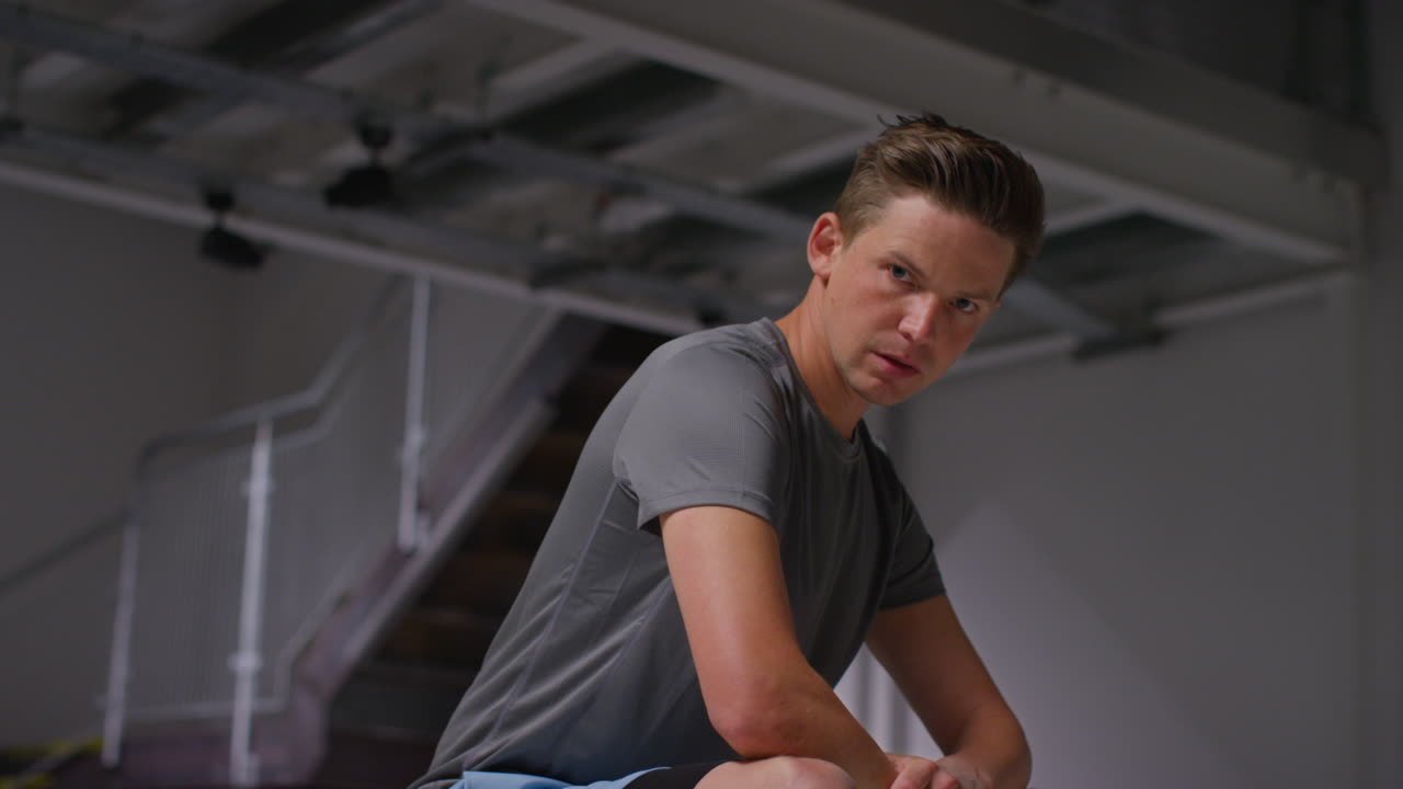 체육관에서 운동 훈련을 하고 옷차림실에 앉아 집중하고 있는 단호한 남자 운동선수 초상화.