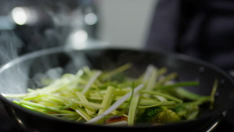 stirring veggies with tweezers in skillet
