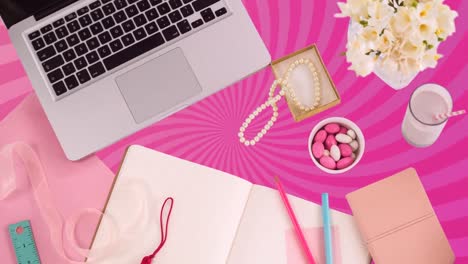 Animation-of-laptop-and-stationery-over-moving-pink-lines