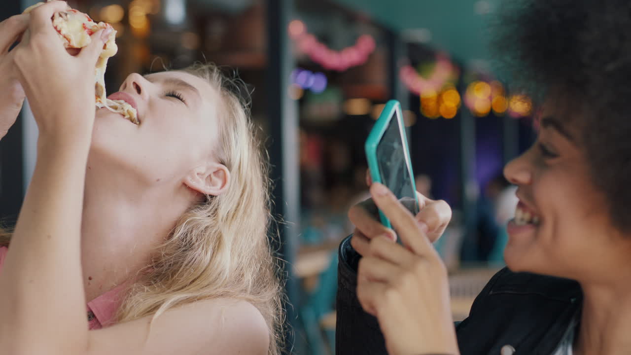 migliori amici che mangiano pizza al ristorante donna che usa uno smartphone che scatta una foto di un amico che si gode il pasto due donne che si divertono a condividere il fine settimana insieme sui social media 4k