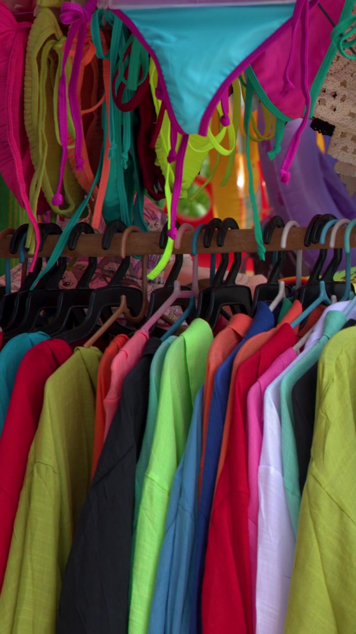 Abbigliamento estivo e costumi da bagno vivaci appesi su espositori in un soleggiato mercato all'aperto a Phuket