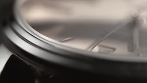 borde plateado de un reloj de pulsera con una esfera blanca, que refleja un haz de luz en movimiento - macro