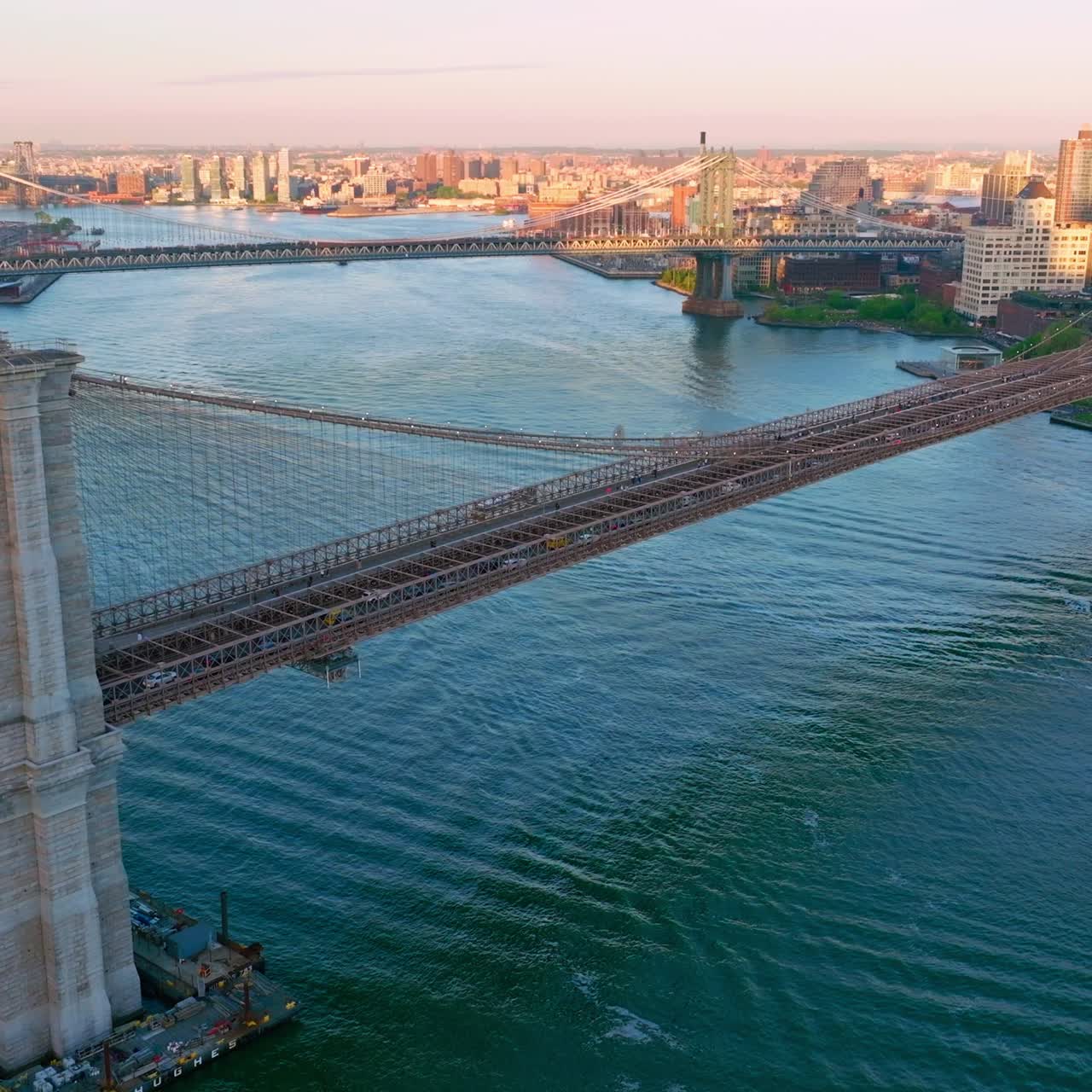 Brooklyn and Manhattan Bridges over East River in New York. Sunlit cityscape at the background. Aerial view
