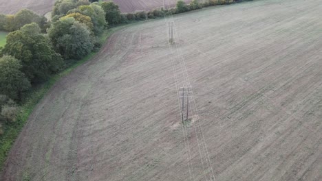 Líneas-De-Energía-Eléctrica-En-Tierras-De-Cultivo-Uk-Drone-Vuela-A-Lo-Largo-De-La-Ruta-De-Las-Líneas-Que-Pasan-A-Través-De-Los-árboles-A-Fines-Del-Verano