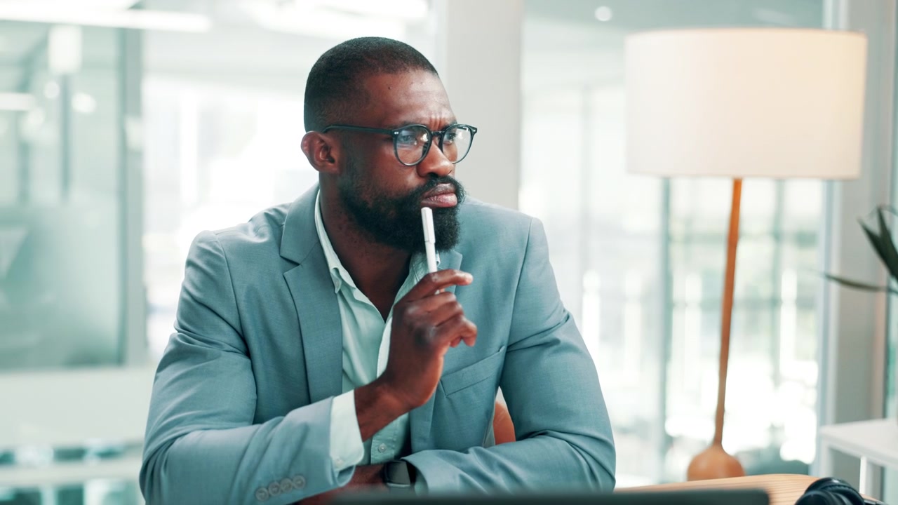 Thoughtful Businessman Sitting at Desk in Modern Office