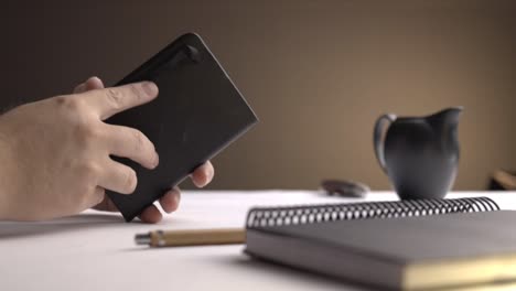 static shot of a man opening a small book and writing down notes