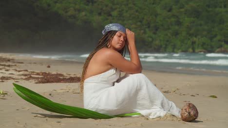 cerrar cámara lenta de una mujer joven en un vestido de playa sentado en la playa en una isla tropical