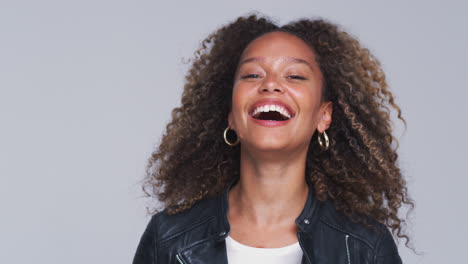 head and shoulders studio shot of woman wearing leather jacket laughing at camera in slow motion