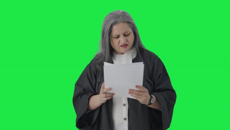 Confused-Indian-senior-female-lawyer-reading-case-reports-Green-screen