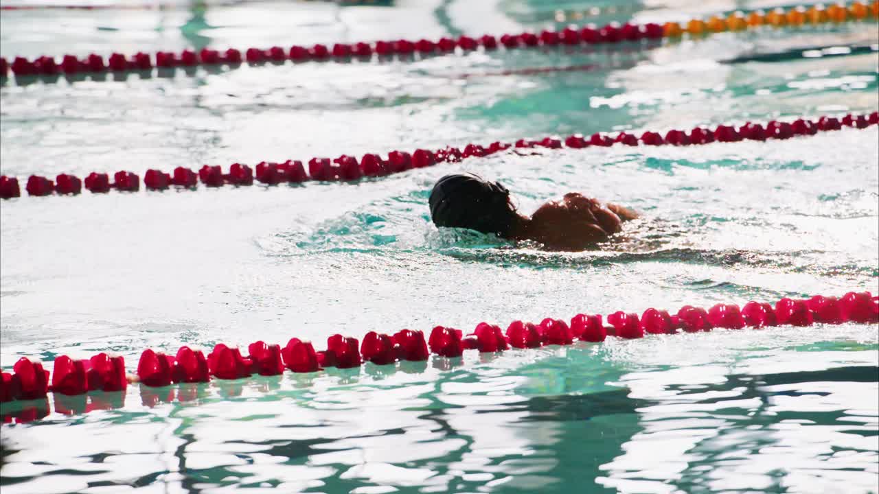 Ein engagierter Schwimmer, der in einem Pool trainiert und kraftvolle Züge und Wasserstörungen in auffälligen Farben der Bahnmarkierungen zeigt