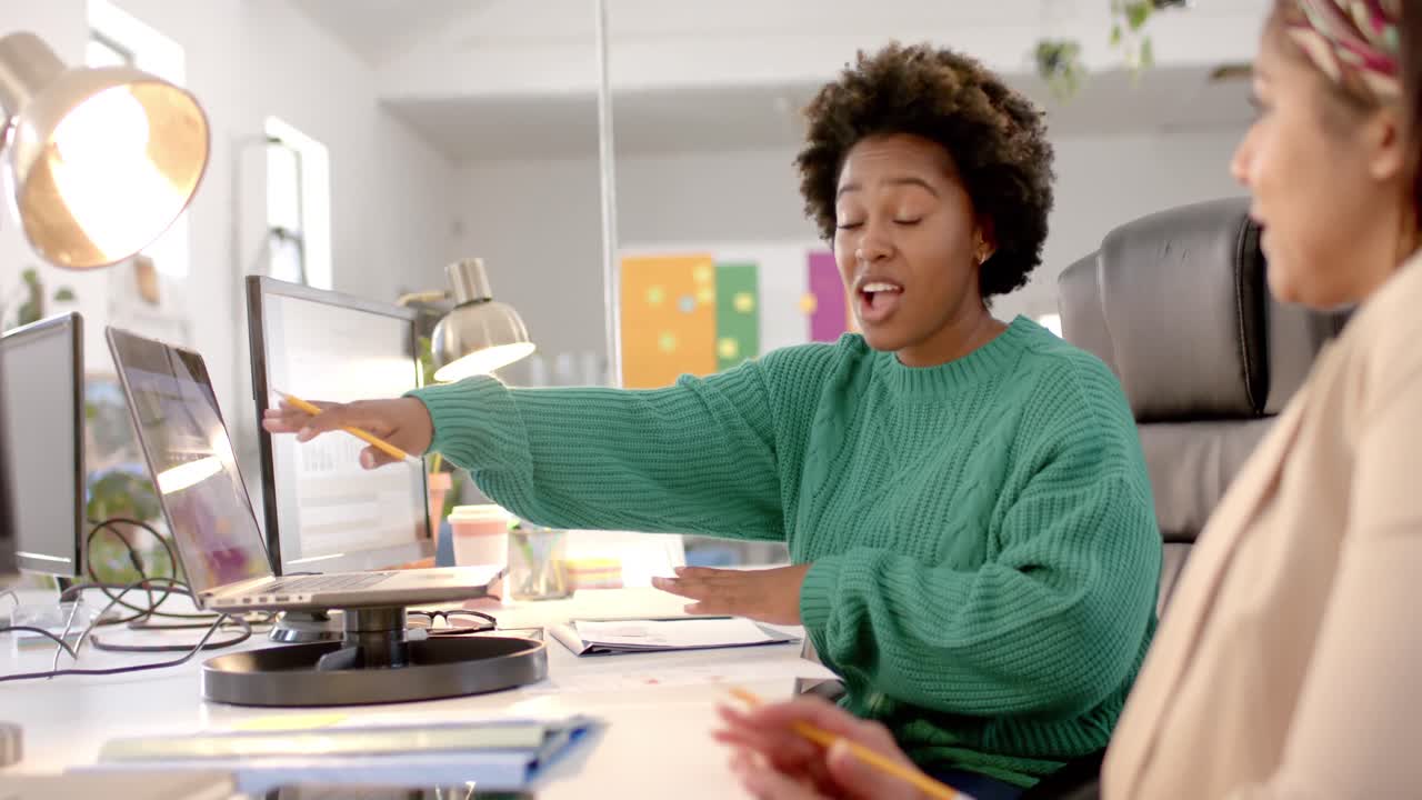 Diverse business female colleagues in discussion using laptop in casual office meeting, slow motion