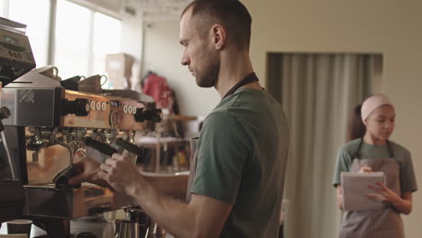 male barista cleaning coffee machine in restaurant